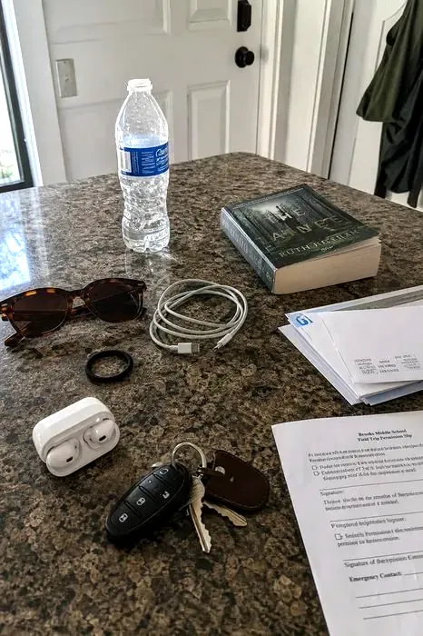 A counter with keys, earbuds and a permission slip, about to be photographed