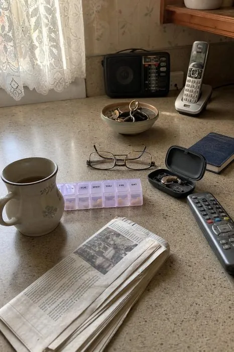 An older parent's kitchen counter with a pill organizer and glasses