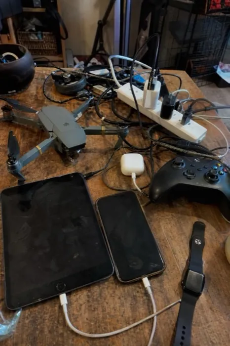 A desk with a drone, tablets, a phone and a watch