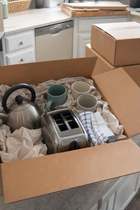 An open moving box with a kettle and mugs